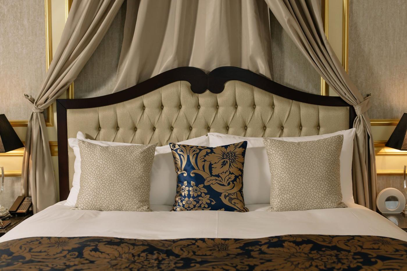 The Bastion Suite, with a tufted headboard and long shuttered windows